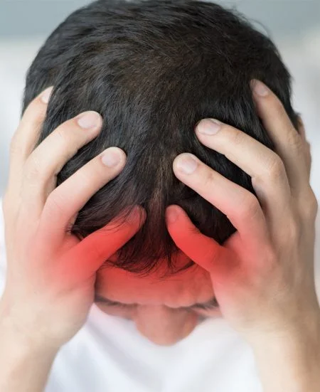 Person gripping their head with both hands, red highlights around temples indicating headache pain.