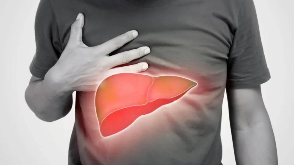Person in gray shirt with hand on upper abdomen and glowing red-orange liver illustration.