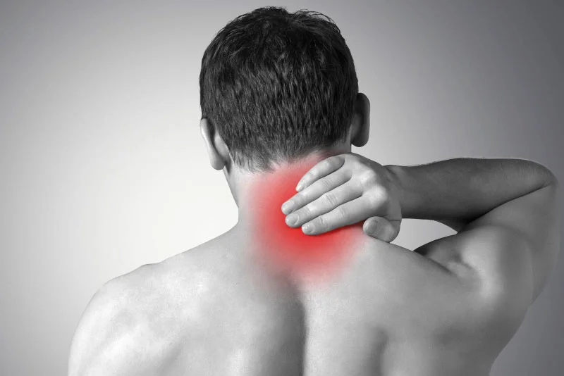 Grayscale image of person holding back of neck with red highlight showing pain.