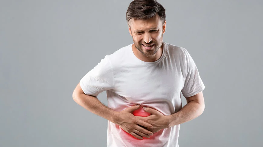 An adult in a white t-shirt clutching their lower abdomen with a red highlight indicating stomach pain.